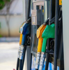 Brandstofpompen met groene, gele en blauwe benzinepistolen bij een tankstation.