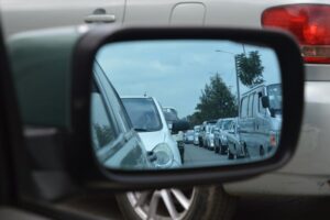 Auto’s in de file gezien via de zijspiegel van een auto op een drukke weg.