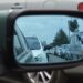 Auto’s in de file gezien via de zijspiegel van een auto op een drukke weg.